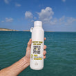 Load image into Gallery viewer, Hand holding a white bottle with a QR code with the Mediterranean sea in the background

