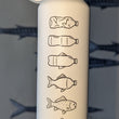 Load image into Gallery viewer, White water bottle with fish and bottle designs on a cardboard box against a background of painted barracudas
