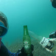 Load image into Gallery viewer, Two scuba divers miming "cheers" with beer bottles found on a debris dive
