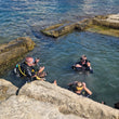 Load image into Gallery viewer, Four divers having a dive briefing on the surface in a square sea pool on Sirens reef, Saint Paul's Bay
