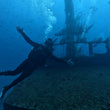 Load image into Gallery viewer, Diver exploring an underwater shipwreck with bubbles rising to the surface.
