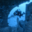 Load image into Gallery viewer, A diver swims between the propeller and the hull of the Um El Faroud shipwreck on the PADI deep diver course
