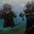 Load image into Gallery viewer, Two divers holding mesh bags full of trash during a debris dive in Malta
