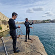 Load image into Gallery viewer, Two PADI rescue divers practicing rope throwing techniques during the PADI rescue diver course in Malta
