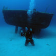 Load image into Gallery viewer, A diver kneels on the sand at 30 metres in front of the P29 wreck, Cirkewwa, Malta
