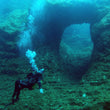 Load image into Gallery viewer, A diver in front of Ben's arch while scuba diving, a famous arch in the north of Malta
