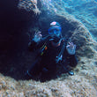 Load image into Gallery viewer, A diver swimming through an arch and giving an "ok" signal on a fun dive at Cirkewwa, Malta
