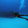 Load image into Gallery viewer, A diver posing in front of the P29 wreck in Cirkewwa, Malta, with clear Mediterranean waters
